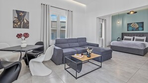 Ein modernes Wohnzimmer mit grauem Sofa, einem Esstisch mit Stühlen, einem Couchtisch und Bildern an den Wänden.