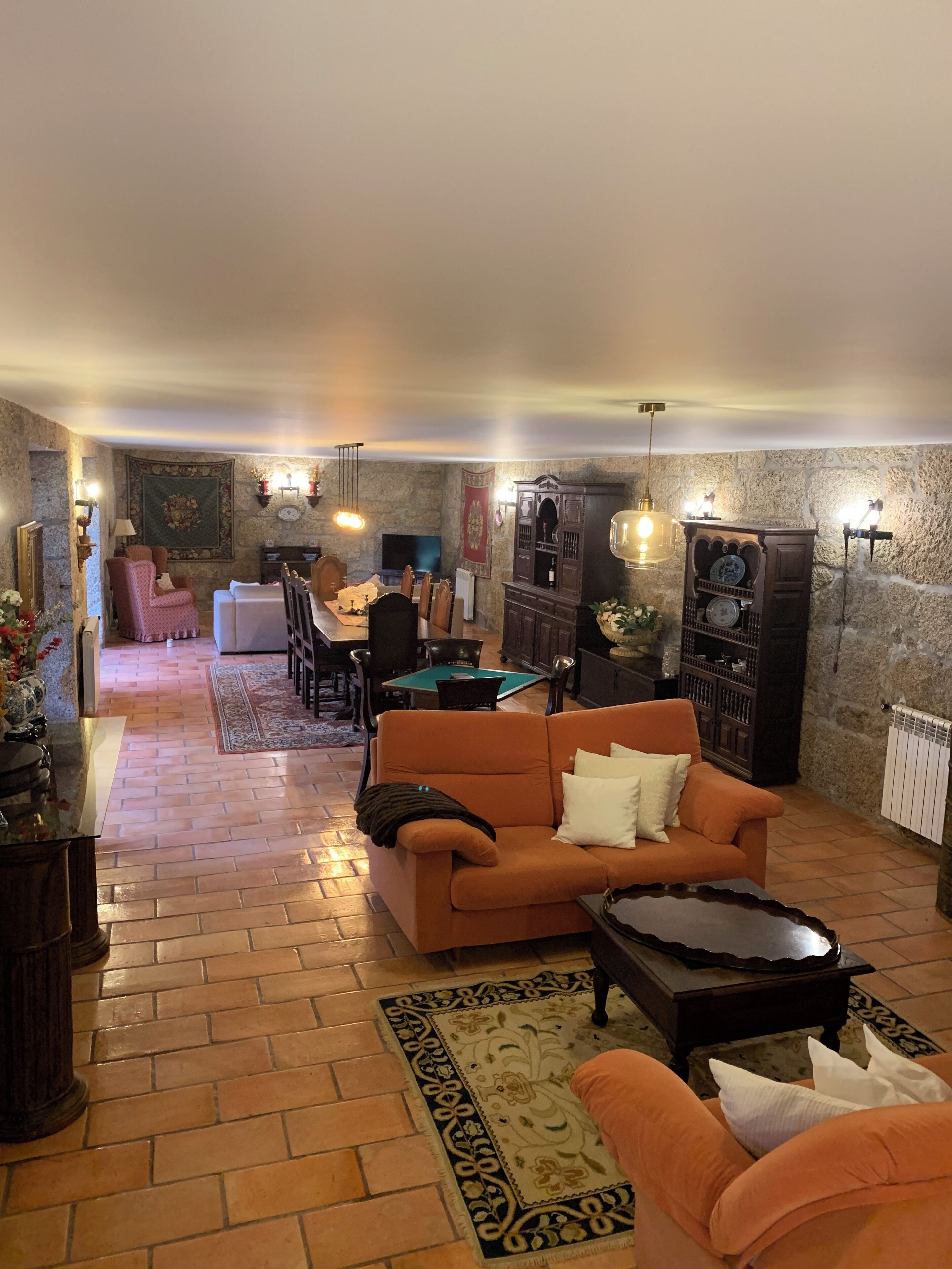 A cozy living room with a sofa, coffee table, and a billiards table in the background.