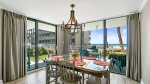 Un'area pranzo con tavolo e sedie in vetro, un lampadario e vista sull'oceano.