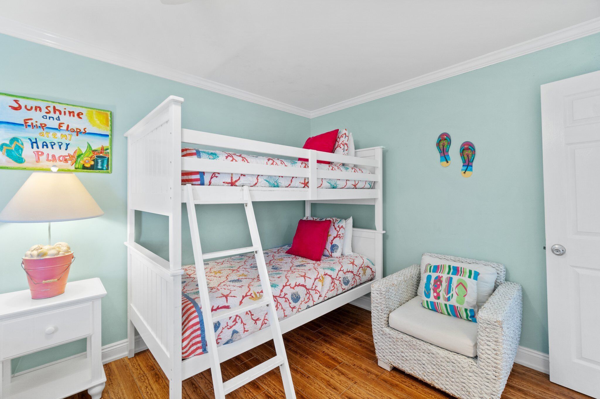 Un lit superposé avec une échelle, une petite chaise et un mur orné d’une affiche.