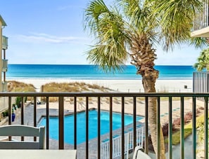 A balcony with a view of a swimming pool and beach.