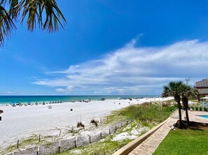 Une plage de sable blanc, un ciel bleu azur et quelques palmiers.