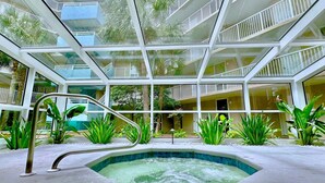 A modern indoor swimming pool with glass railings and a view of the surrounding building.
