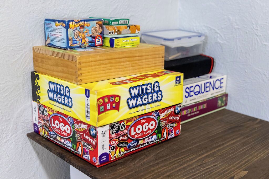 A stack of board games including Wits & Waggers, The Logo Board Game, and Sequence.