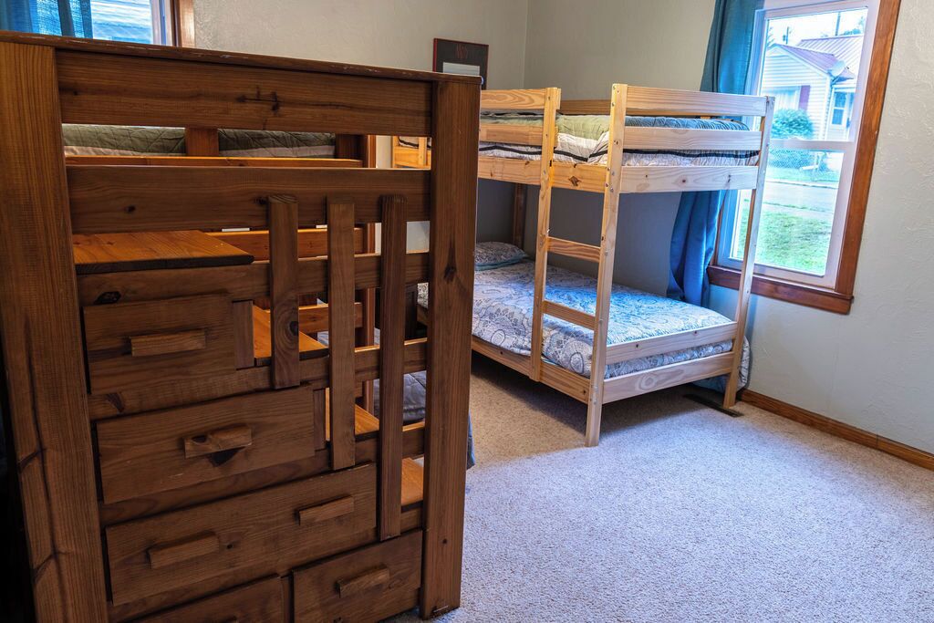 A room with a bunk bed and a wooden playpen.