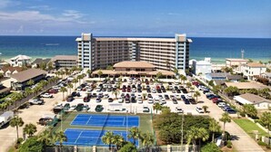 Un hotel grande con estacionamiento y cancha de tenis.