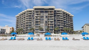 Un hôtel à plusieurs étages doté de balcons, situé en bord de mer et équipé de parasols.