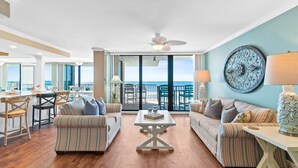 Un vaste espace de vie avec balcon, des canapés à rayures, une table basse et un coin repas comprenant des chaises et une table.