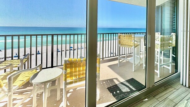 A balcony with a view of the beach and ocean.