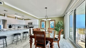 A modern kitchen with white cabinets, a central island, and bar stools.