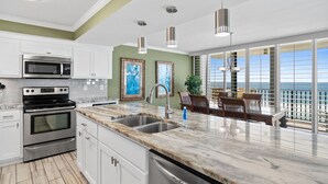 A modern kitchen with white cabinets, stainless steel appliances, and a marble countertop.