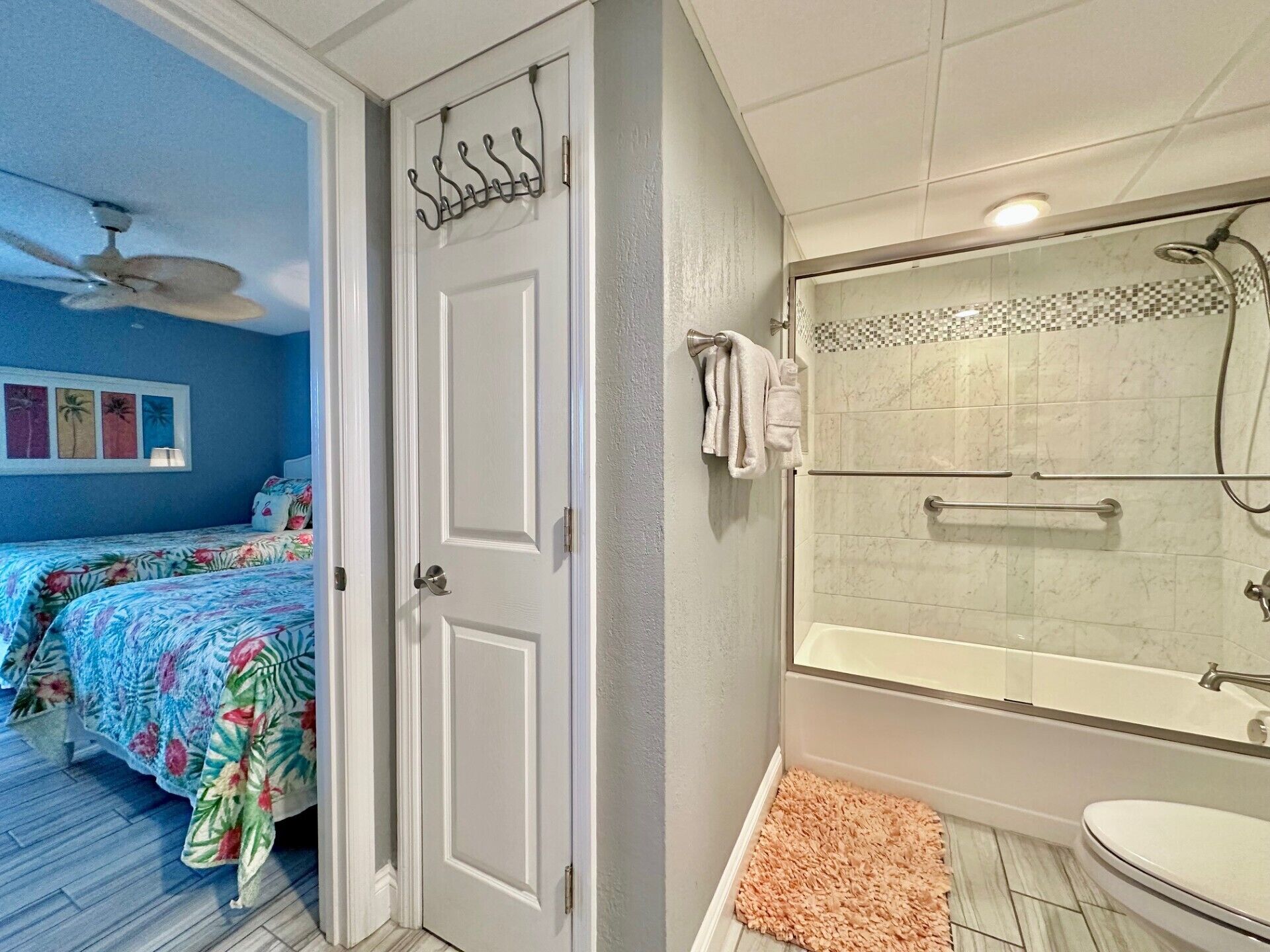 Une chambre à coucher avec un lit, un ventilateur de plafond et une porte dotée d’un porte-manteau.