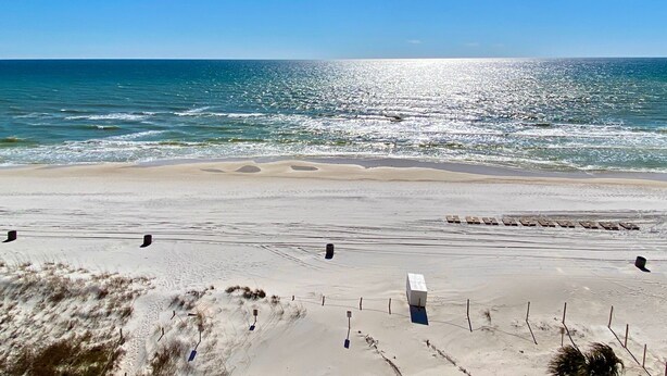 A beach with a white building, a sandy shore, and the ocean.