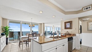 Una cocina amplia con una isla grande, muebles blancos y vista al océano.