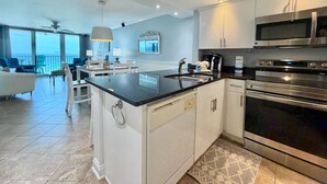Una cocina moderna con una isla central, electrodomésticos de acero inoxidable y vistas al exterior.