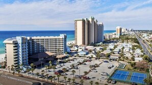 A coastal resort area with multiple high-rise buildings, a parking lot, and a tennis court.