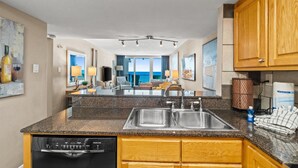 A kitchen with granite countertops, stainless steel sinks, wooden cabinets, and a Bosch dishwasher.