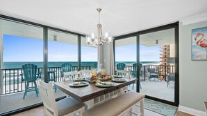 Un comedor con vistas al océano, una araña y una mesa dispuesta para cuatro comensales.