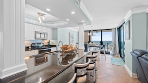Una cocina moderna con una isla central, taburetes de bar y vistas al exterior.