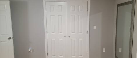 A room with a wooden floor, two white doors, and a large mirror on the wall.