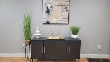 A black cabinet with gold handles, a white vase, and a gold tray on top.