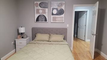 A bedroom with a bed, bedside table, lamp, and two abstract wall art pieces.