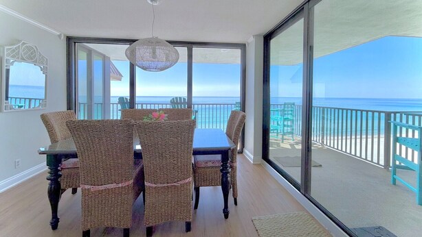 Un balcon avec vue sur l’océan, des fauteuils en osier, une table et un luminaire suspendu.