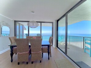 Ein Balkon mit Blick auf den Ozean, Korbmöbel, ein Tisch und eine Hängelampe.