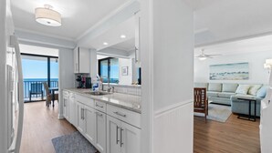 Une cuisine moderne avec des meubles blancs, un grand îlot central et une vue sur l’extérieur.