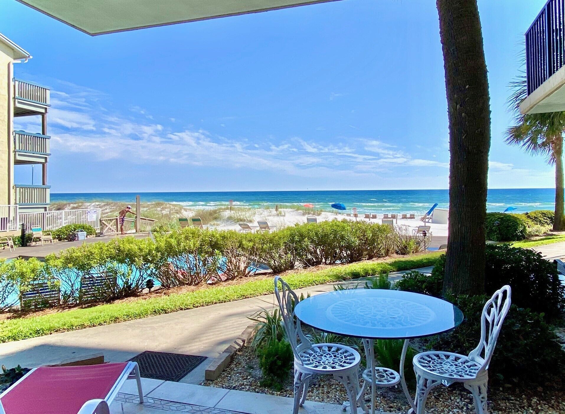 A patio with a table and chairs overlooking a beach.