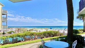Eine Terrasse mit Tisch und Stühlen mit Blick auf einen Strand.
