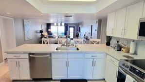 A modern kitchen with white cabinets, a large island with a sink, and a built-in oven. - Saida 3601 3 Bedroom Home by RedAwning (South Padre Island)