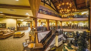 A multi-level hotel lobby with a grand staircase, wooden beams, and a Christmas tree. - 2BD/Wisconsin Dells - Access to Water Parks! (Baraboo)