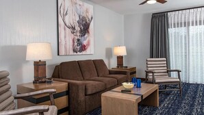 A hotel room with a brown sofa, two side tables with lamps, a wooden coffee table, a chair, and a large window with curtains. - 2BD/Wisconsin Dells - Access to Water Parks! (Baraboo)