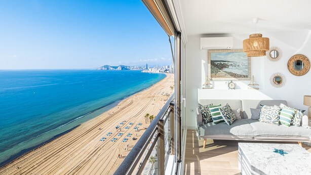 Een balkon met uitzicht op een strand en stadshemelbeeld.