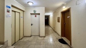 Pasillo de hotel con puertas, un letrero que indica 'Piso 1' y señalización de salida de emergencia.