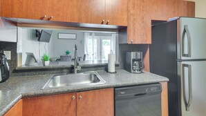 Una cucina moderna con mobili in legno, un lavello in acciaio inossidabile, una lavastoviglie e un frigorifero.