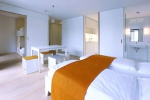 A modern hotel room with a bed, a desk, and a mirror.