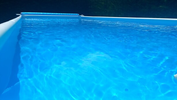 Vista clara de una piscina con un tono azul, rodeada de un entorno oscuro.