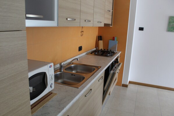 A kitchen with a microwave, double sink, and stainless steel appliances. - APARTMENT LILIA 3 - ground floor CIN:IT022229C2PWORAISW (Tiarno di Sopra)