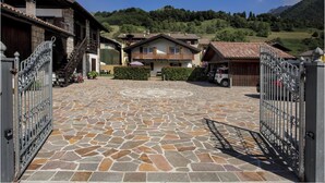 Una entrada empedrada a una zona residencial con casas y una montaña de fondo.