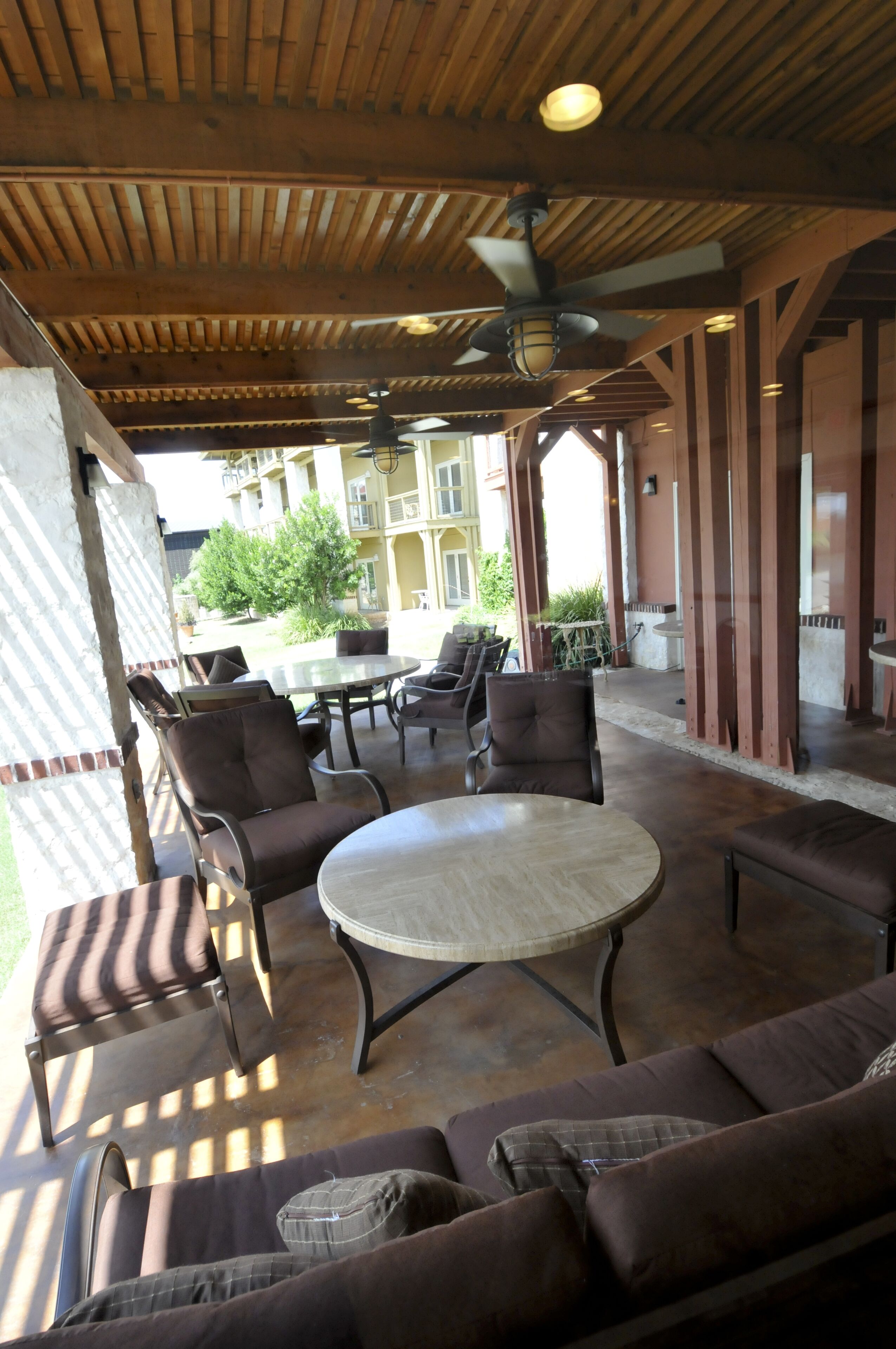 Un área de patio al aire libre con una mesa redonda y sillas, un sofá y un ventilador de techo.