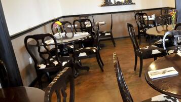 A dining area with round tables and chairs, a mirror on the wall, and a tiled floor.