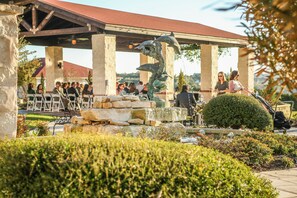 Un espacio al aire libre con pilares de piedra, una fuente y un porche cubierto.