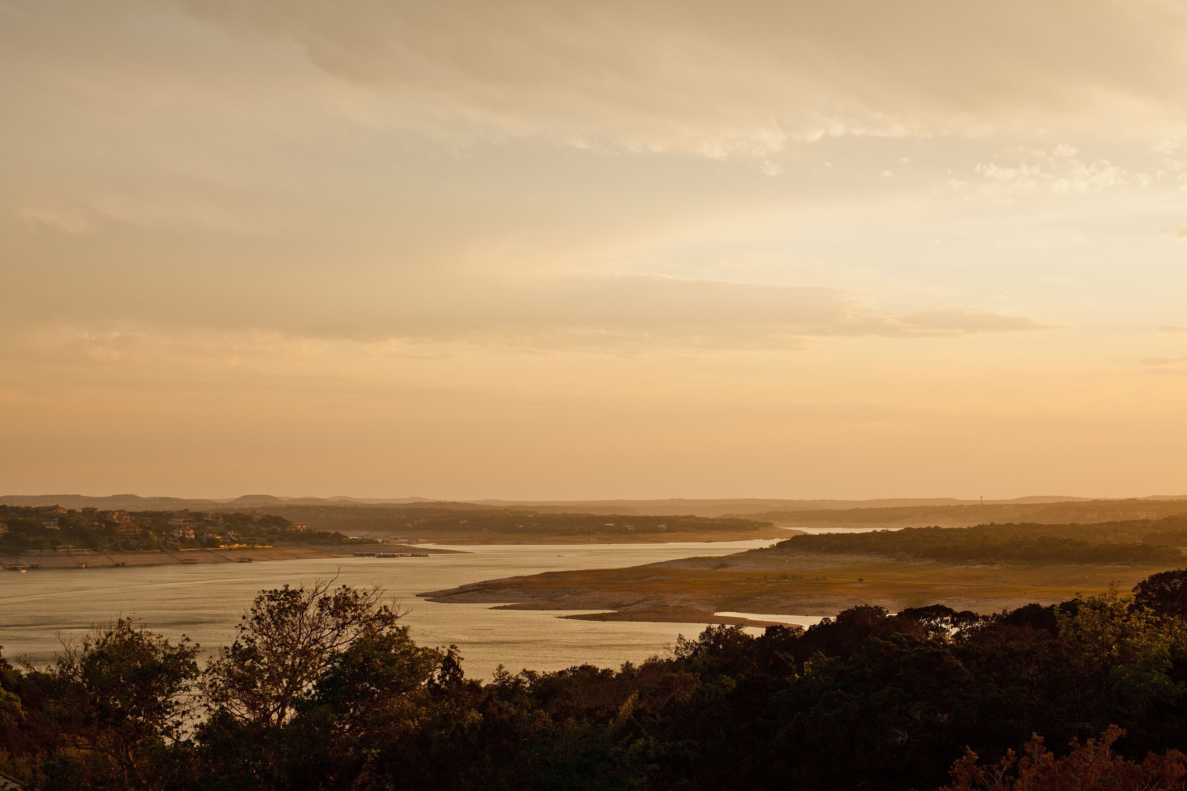 A river landscape with a distant shoreline and trees in the foreground.
