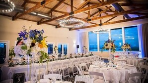 Ein Banketthaus mit runden Tischen, weißen Stühlen und floralen Tischdekorationen.