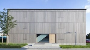 Ein modernes Gebäude mit Flachdach, großen Fenstern und einem zentralen Eingang.