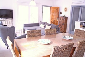 Un salon avec un canapé, des fauteuils, une table en bois et un téléviseur.