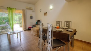 Un comedor con una mesa dispuesta para dos personas, una mesita auxiliar y una silla con estructura metálica.