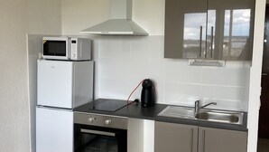 A compact kitchen with a microwave, oven, and sink.